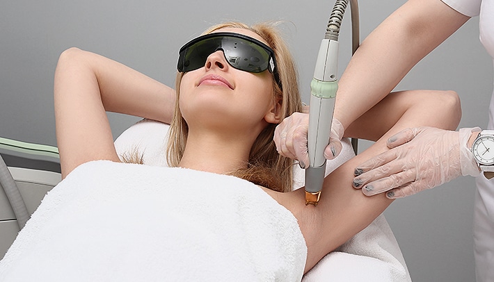 Stock photograph of models: a gloved hand examines small moles on a bare shoulder